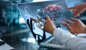 People pointing at a laptop screen of a brain while holding a folded stethoscope