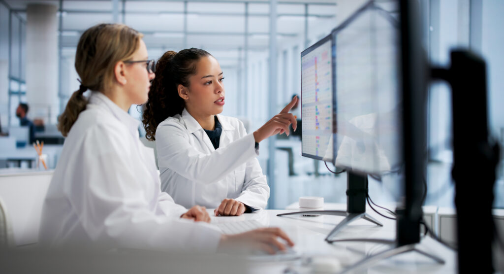 Two nurses reviewing a monitor with health data.