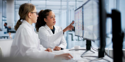 Two nurses reviewing a monitor with health data.